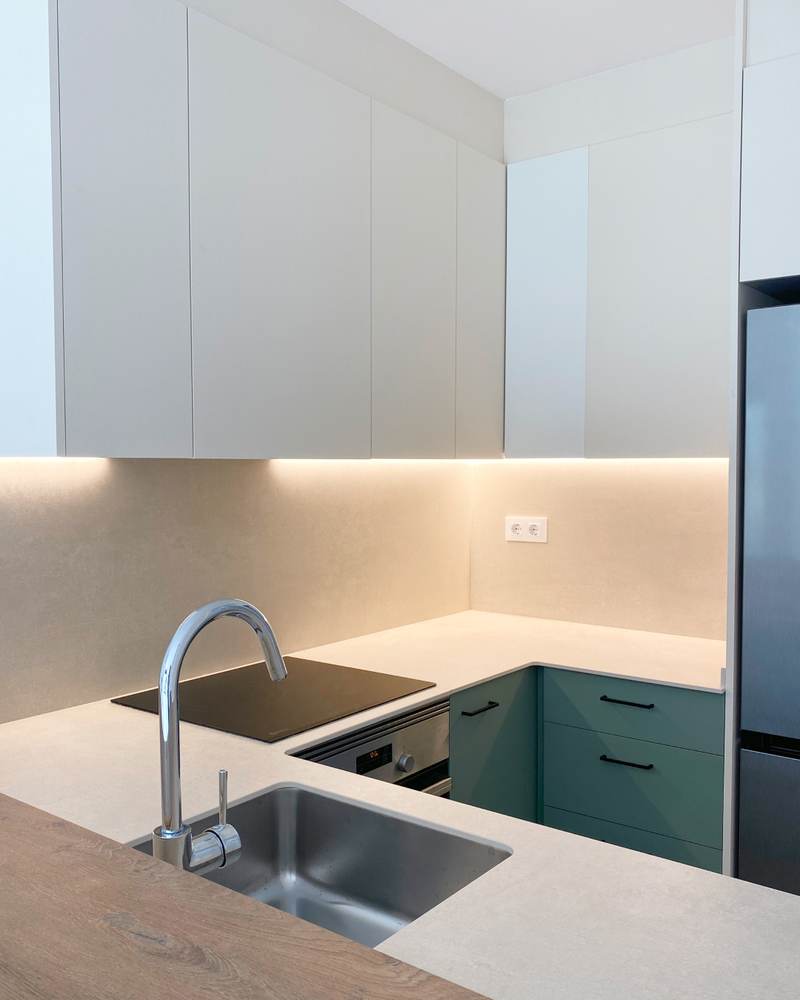 Cocina reformada con muebles verdes y encimera clara