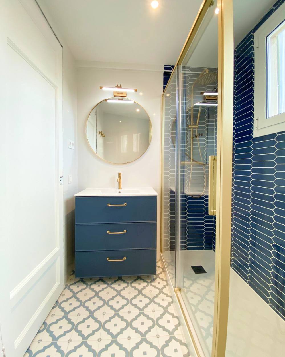 Baño reformado por Dom In House en Barcelona: azulejo azul, grifería dorada y suelo hidráulico
